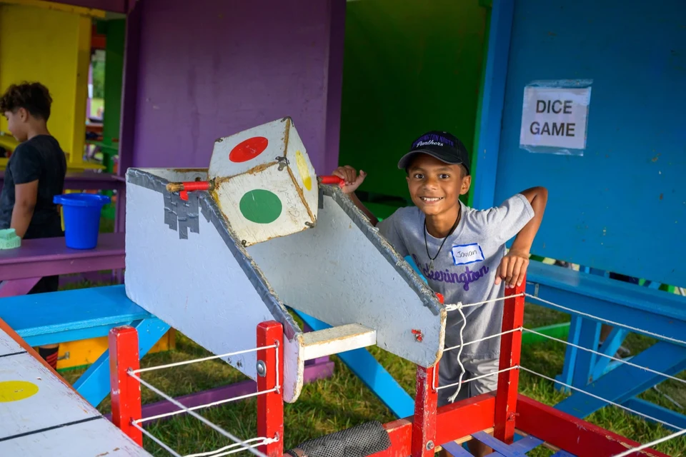 Child smiling beside the dice game prize board
