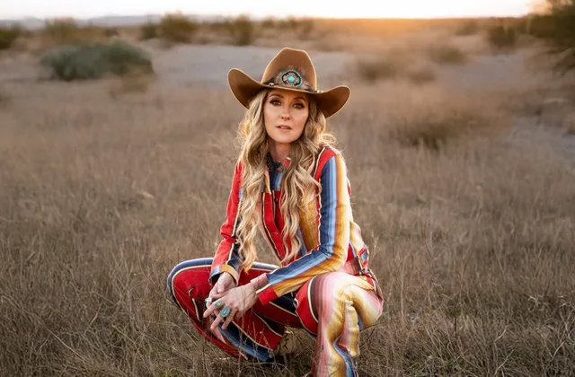 Lainey Wilson tribute performer seated in a desert field