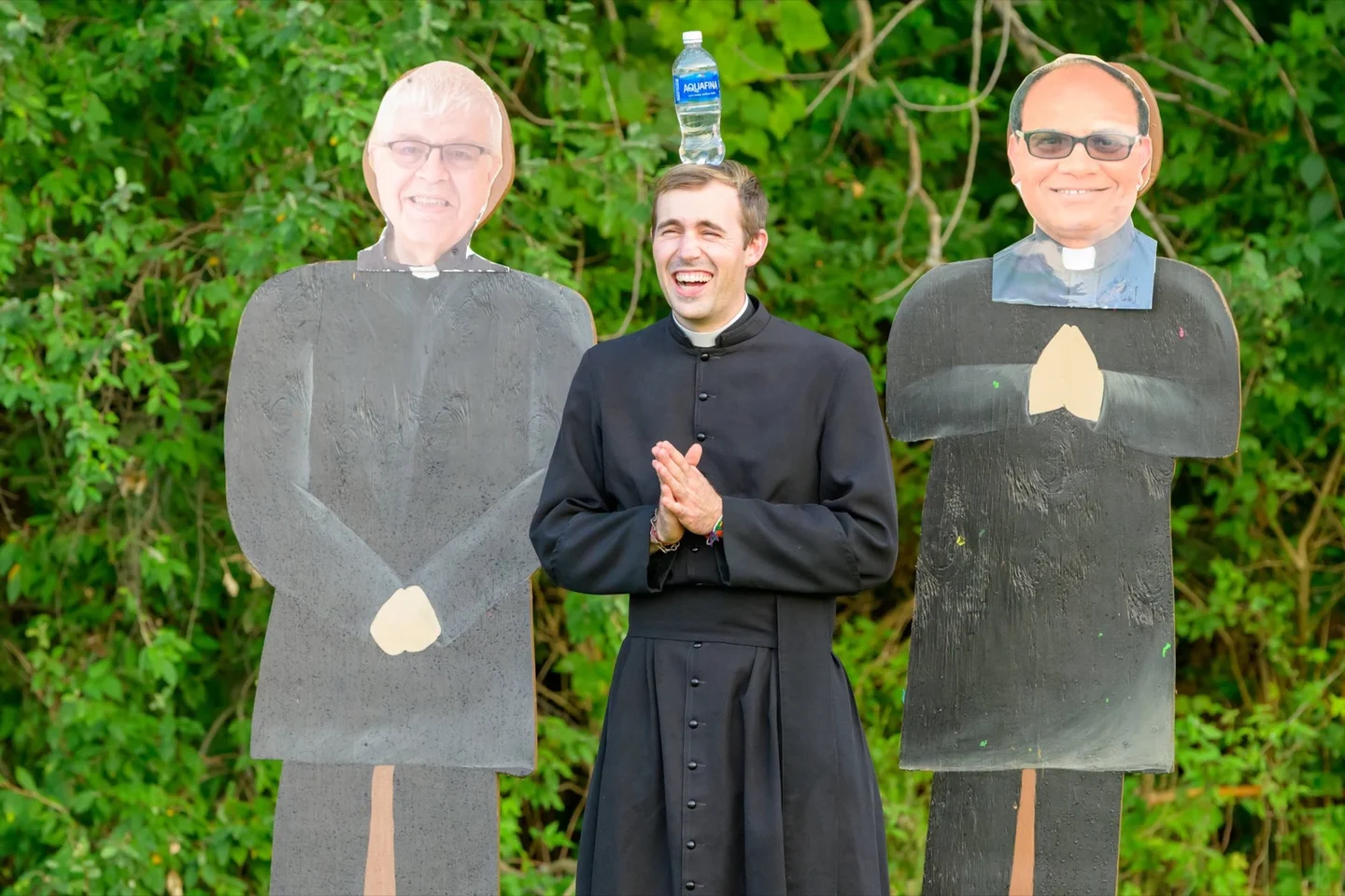 Priest standing between two priest cutouts for Pastor Blaster