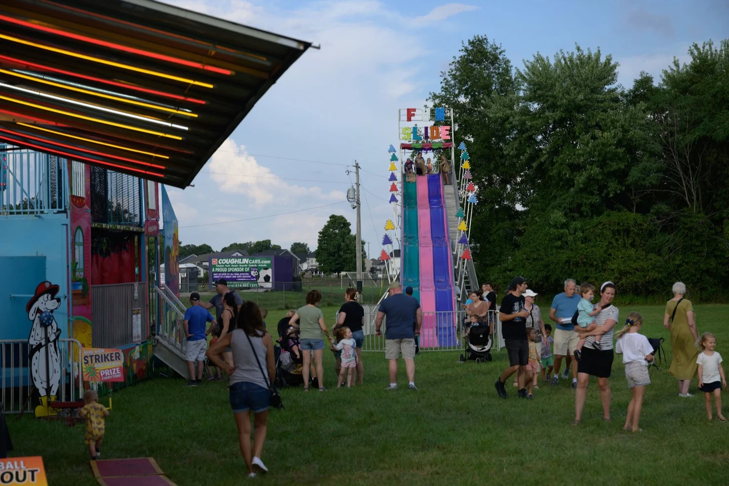 Families walking near carnival rides and a giant slide